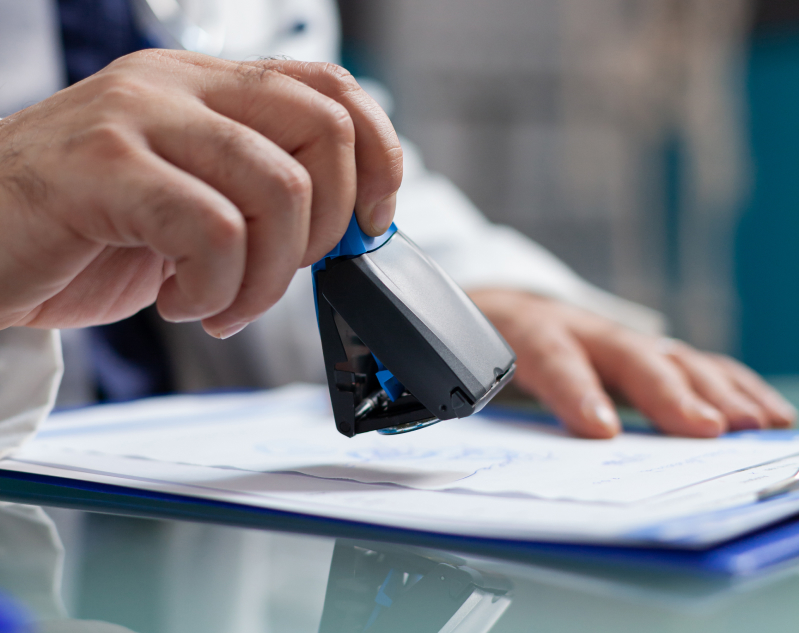 doctor-holding-medical-stamp-put-prescription-paper-health-care-exam-hand-physician-putting-seal-checkup-report-giving-medicine-patient-consultation-close-up 1 (1)